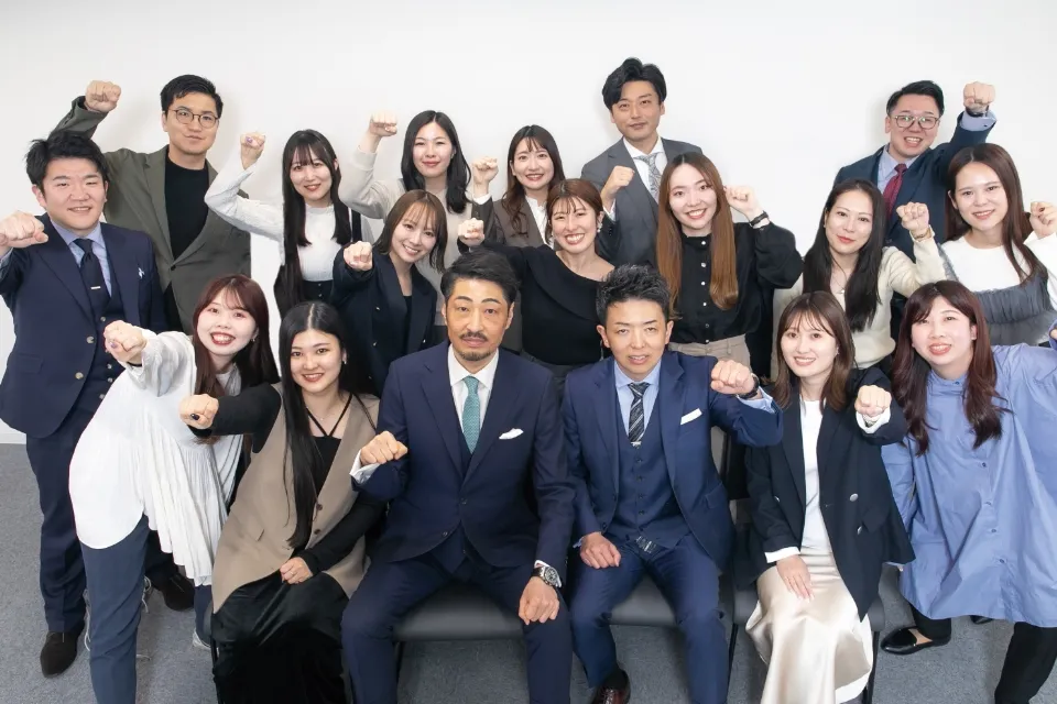 FRONTIER GROUPの社員一同が揃ってガッツポーズをしながら笑顔で写っている集合写真。