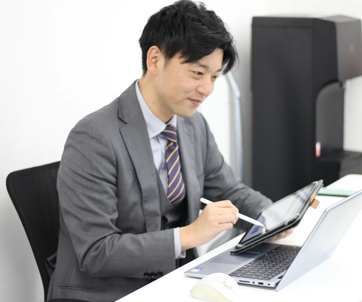 グレーのベストとネクタイを着用し、会議で真剣に話をしている男性社員の横顔。