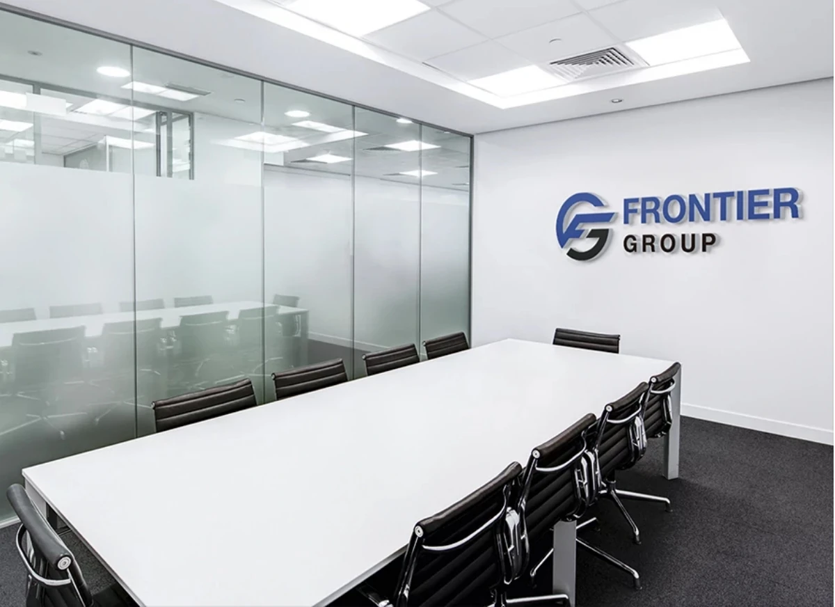 白い壁に「FRONTIER GROUP」のロゴと社名が掲げられた、清潔感のある会議室。長い白いテーブルを囲んで、黒い革張りの椅子が整然と並んでいる。